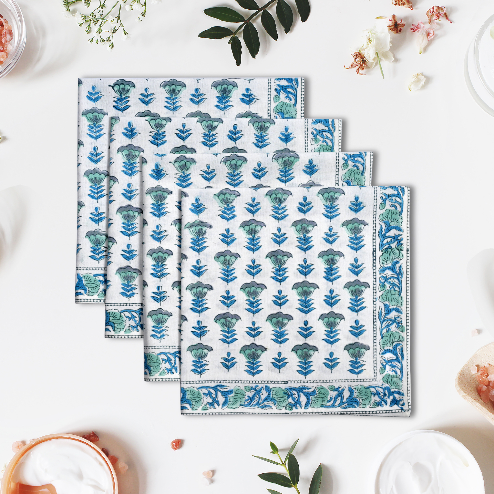 Set of three floral-patterned towels on a white surface with decorative elements.