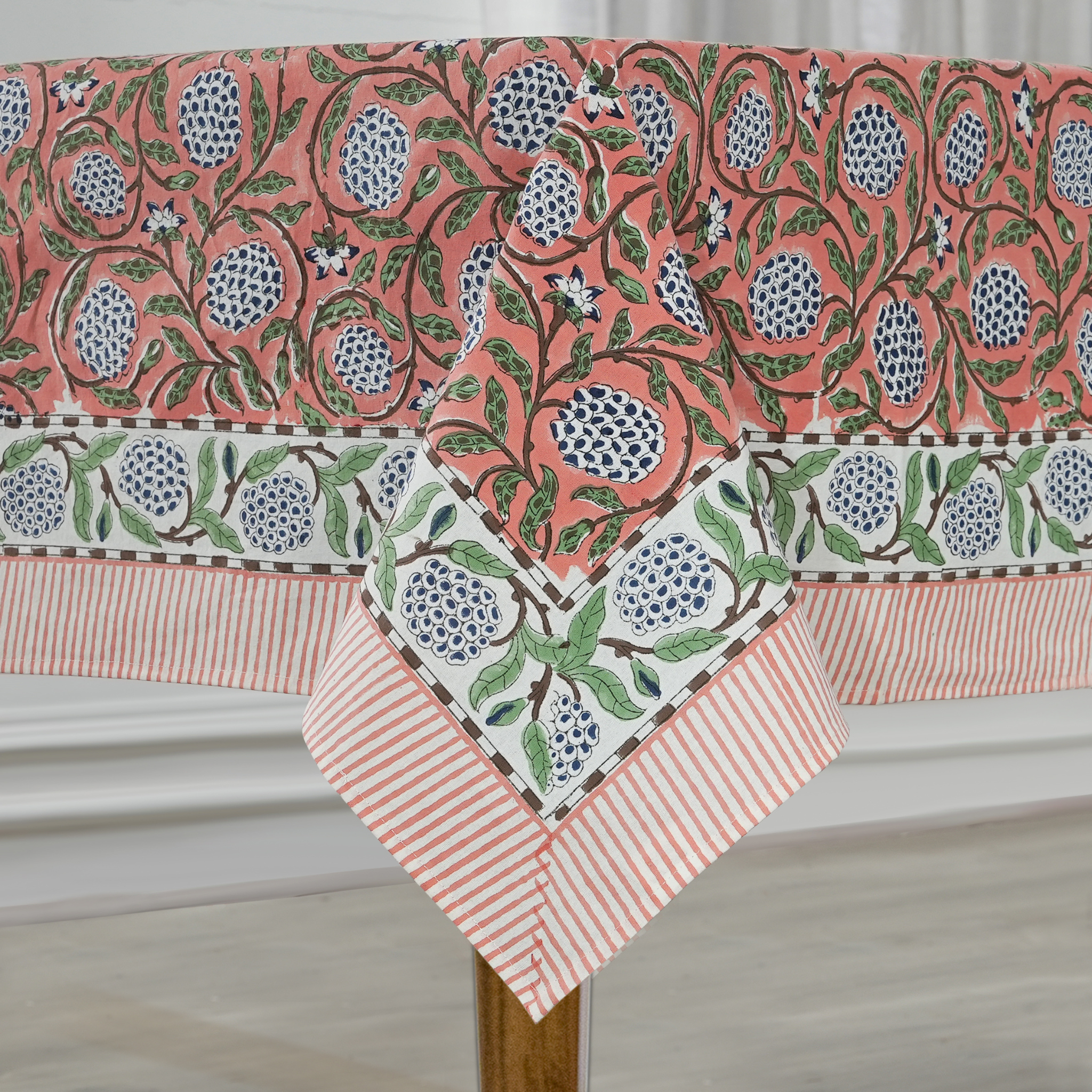 Decorative tablecloth with floral and striped patterns on a wooden surface.
