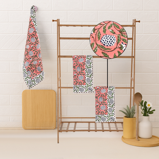 Decorative towels with floral patterns hanging on a rack against a white tiled wall.