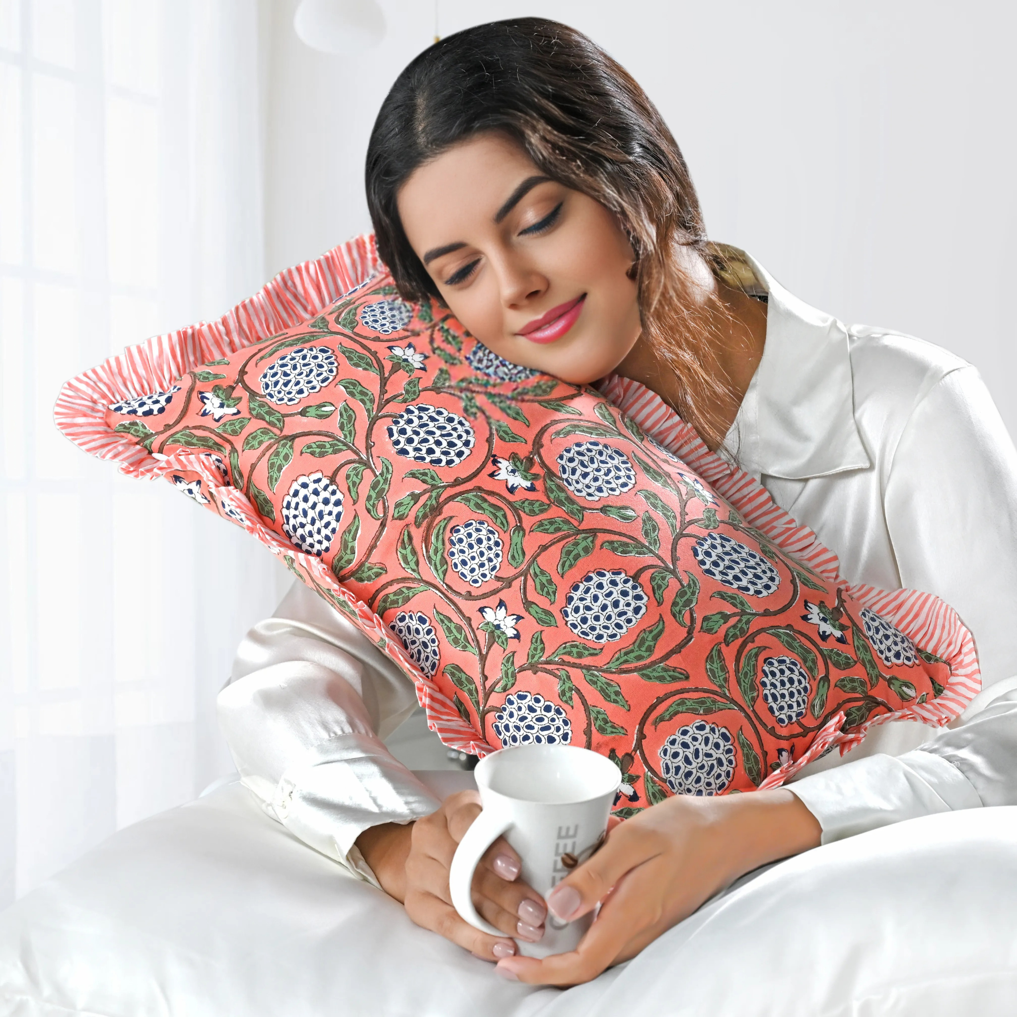 Woman holding a floral-patterned pillow and a mug on a white background