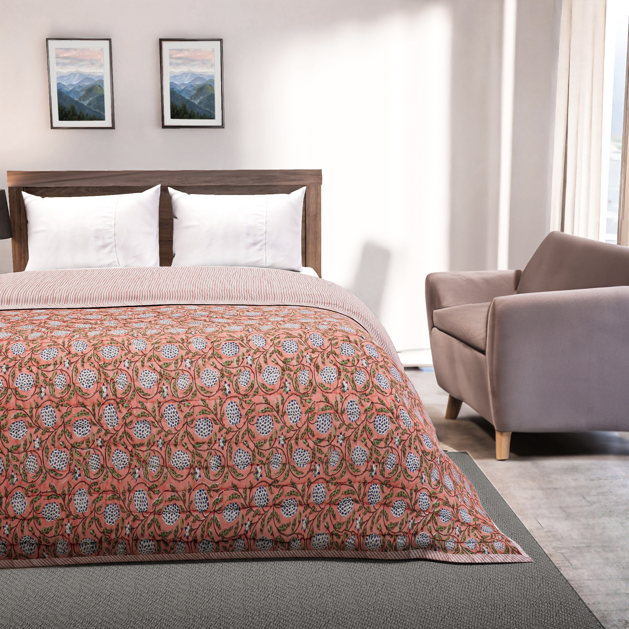 Bedroom with a bed featuring a patterned quilt, a chair, and framed pictures on the wall.