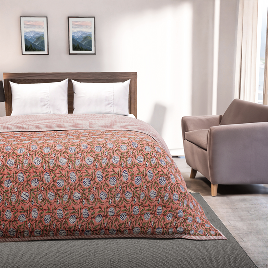 Bedroom with a bed featuring a patterned quilt, a chair, and framed pictures on the wall.