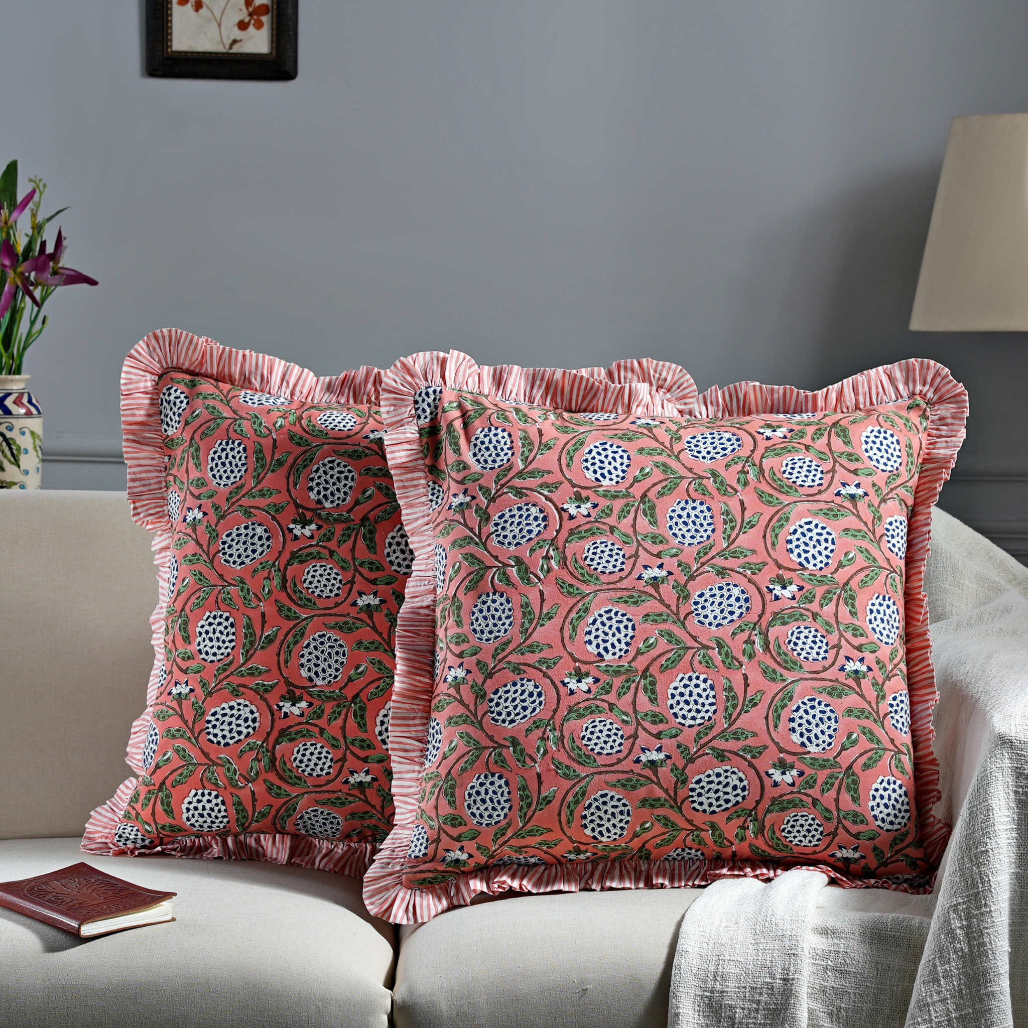 Decorative pillows with floral patterns on a sofa against a gray wall.