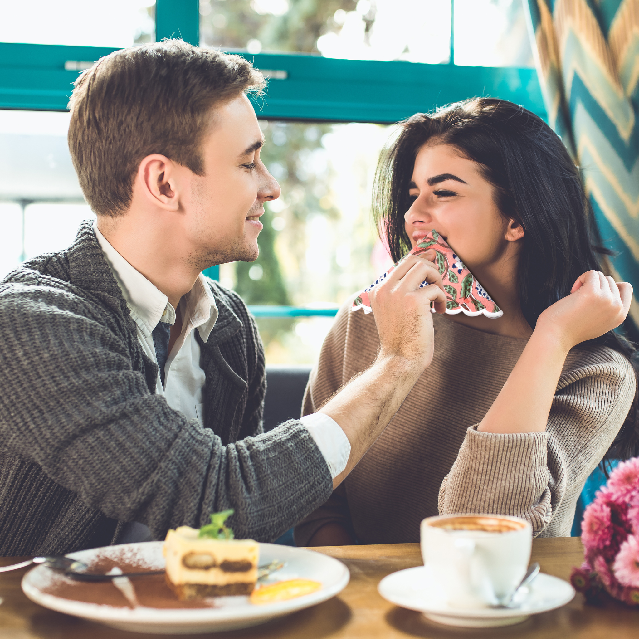 Man and woman sharing a moment at a cafe with a cup of coffee and cake.