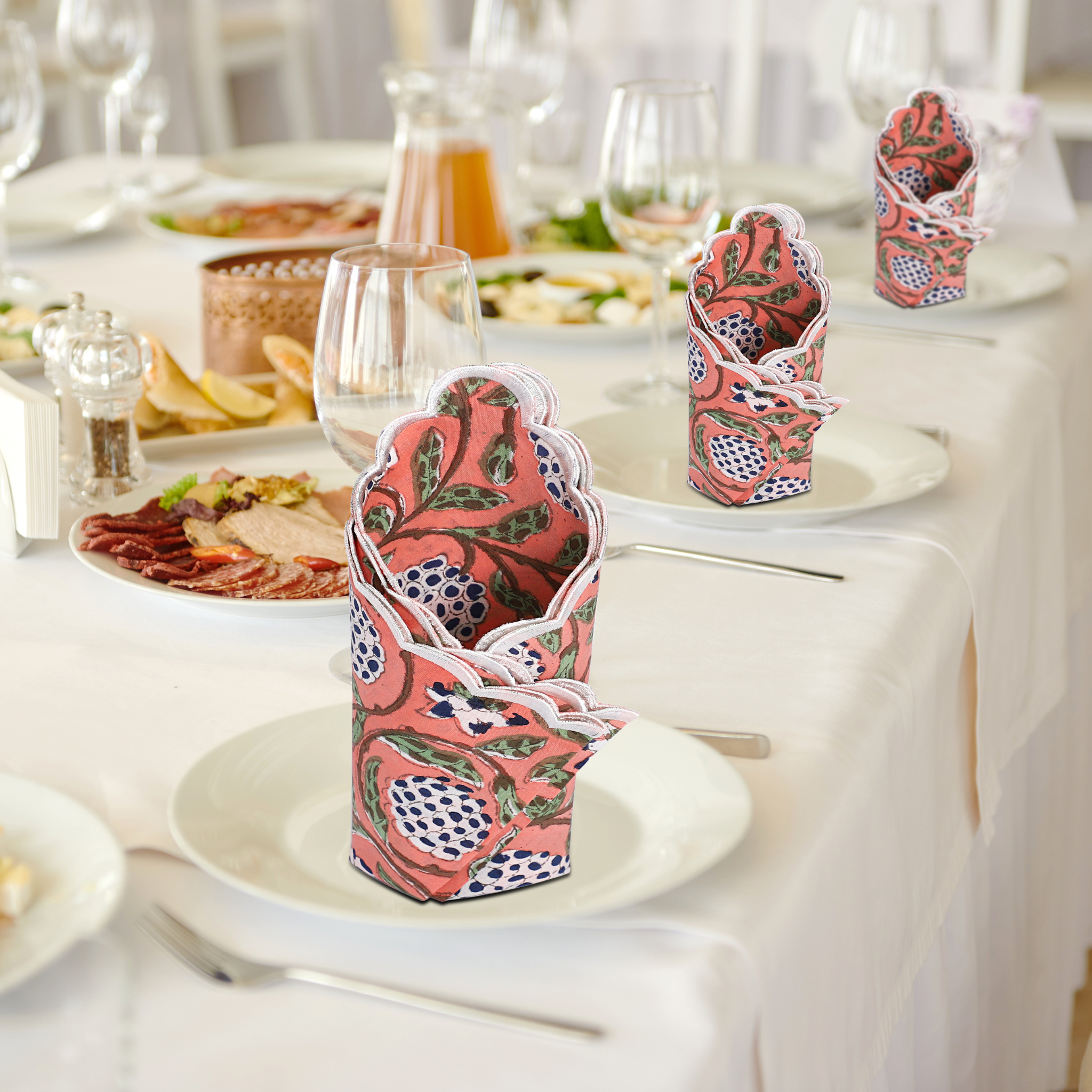 Decorative pink and green napkin holders on a table with plates and glasses.