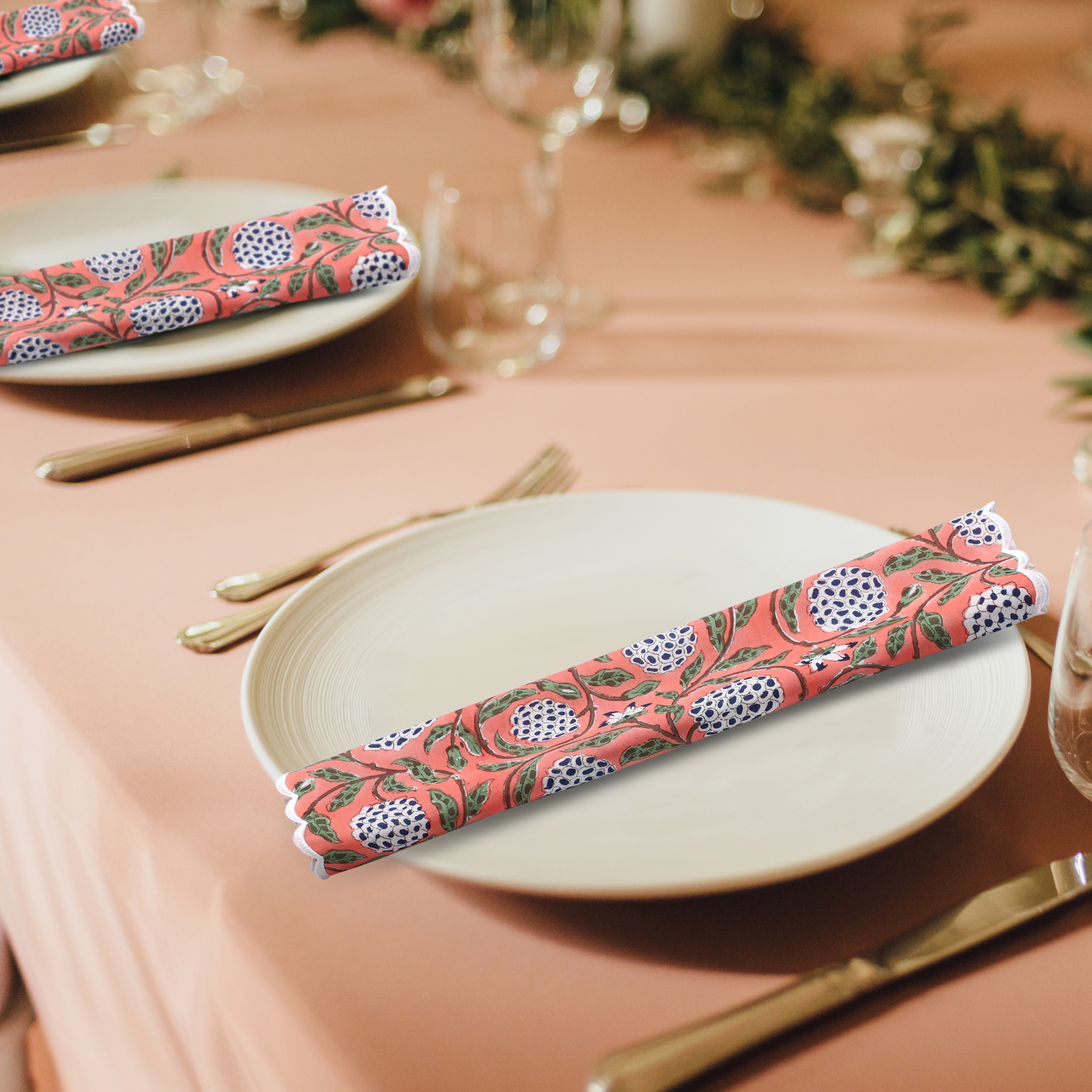 Decorative pink floral napkin on a white plate with a peach-colored tablecloth.