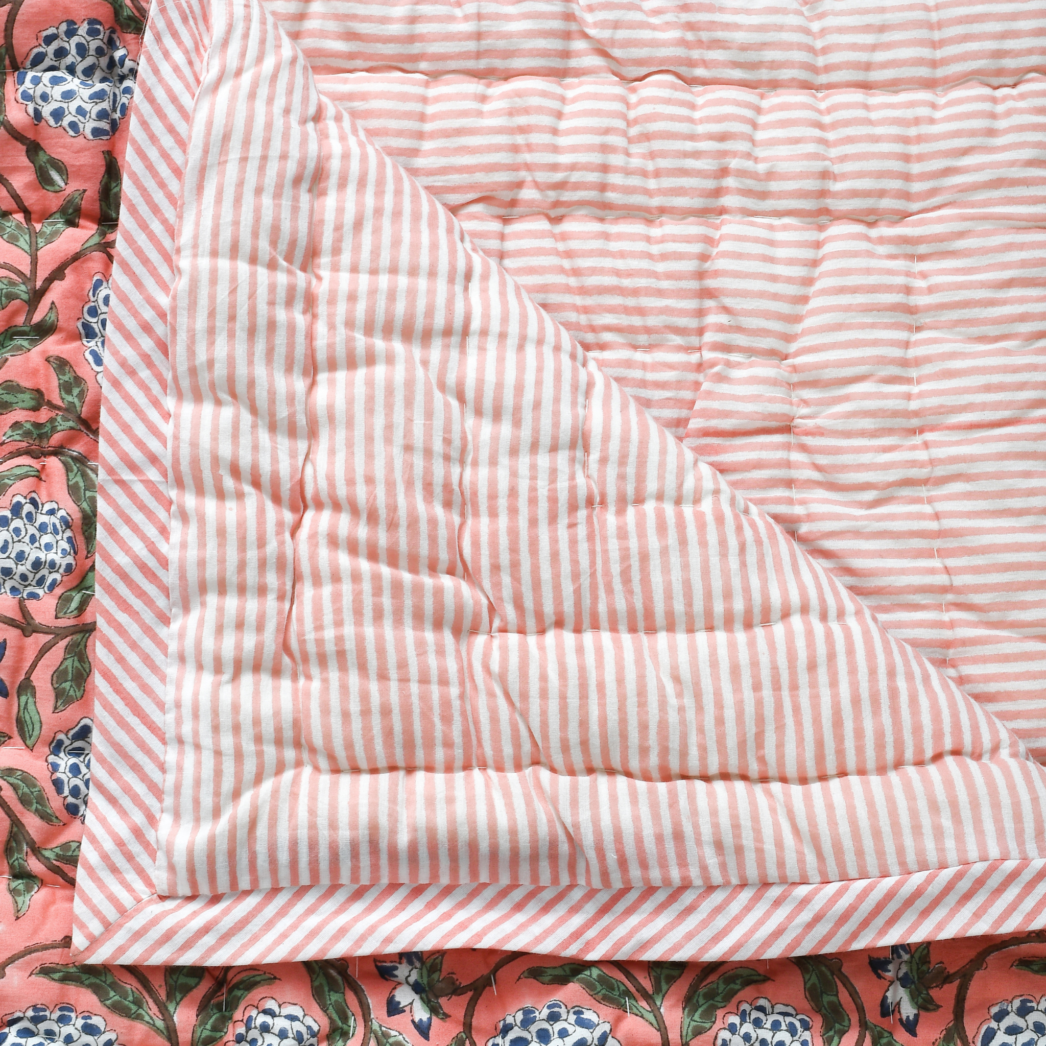 Quilt with pink and white stripes on a floral background