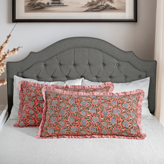 Large block print cotton pillows styled on gray upholstered bed.