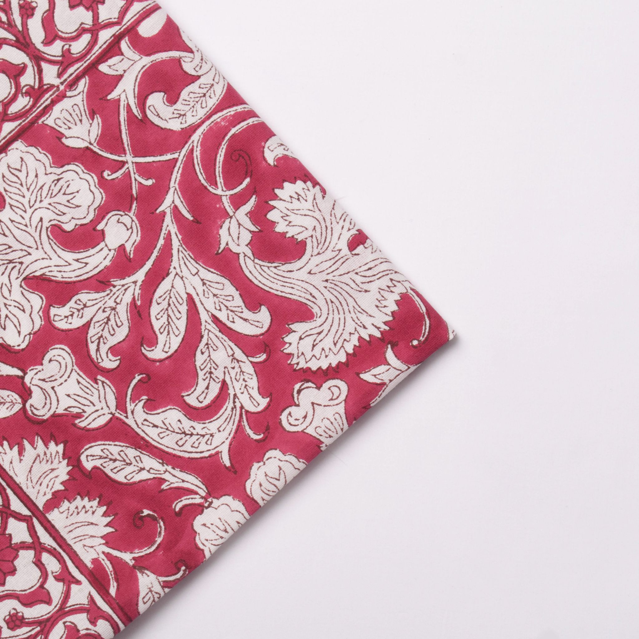 Red fabric with white floral patterns on a light gray background