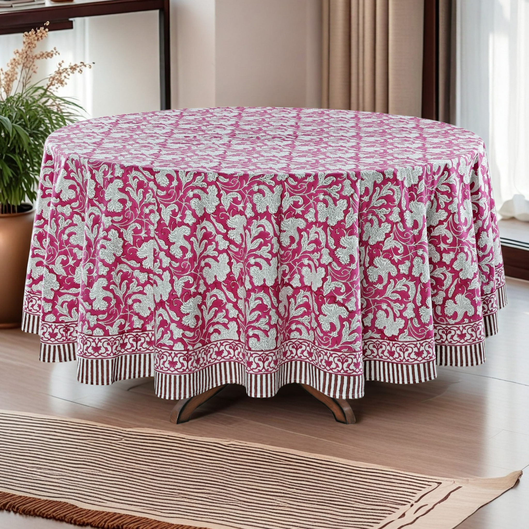 Round table covered with a pink and white floral patterned tablecloth in a room setting.