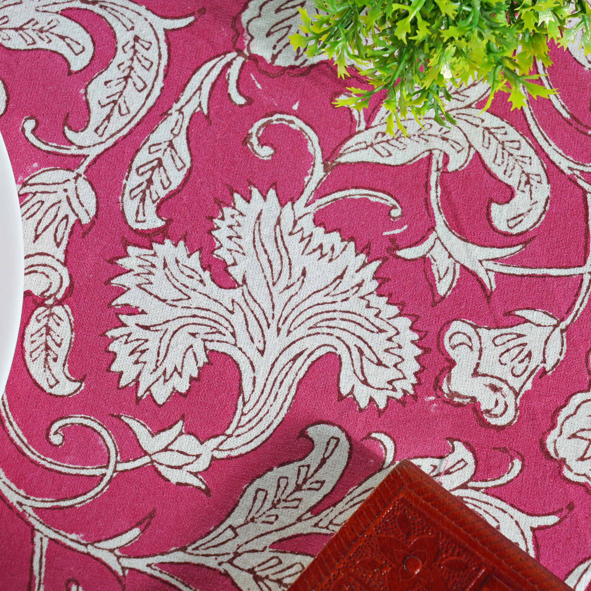Pink fabric with white floral patterns and a plant in the corner