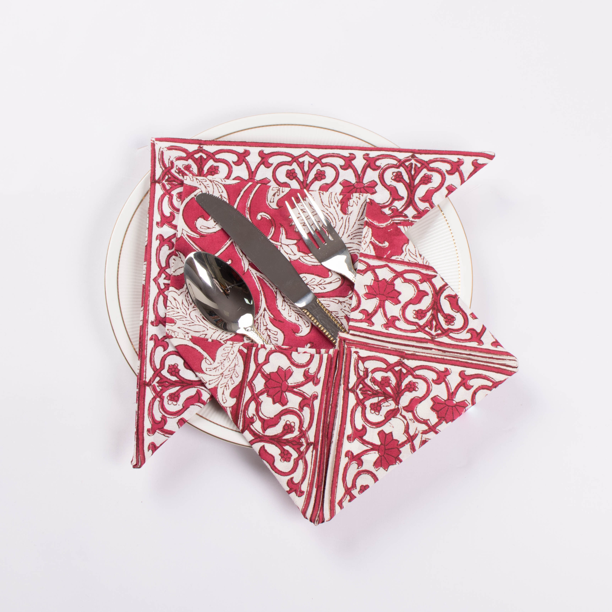 Red and white patterned napkin with silver cutlery on a white background