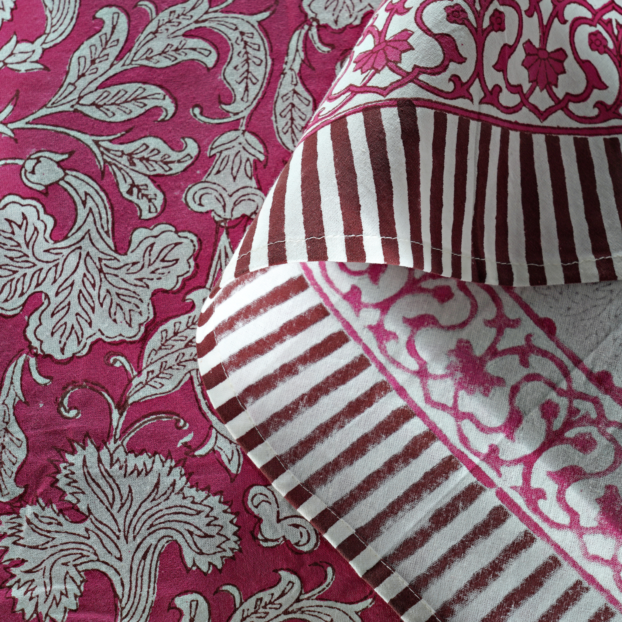 Close-up of patterned fabric with floral and striped designs on a pink background