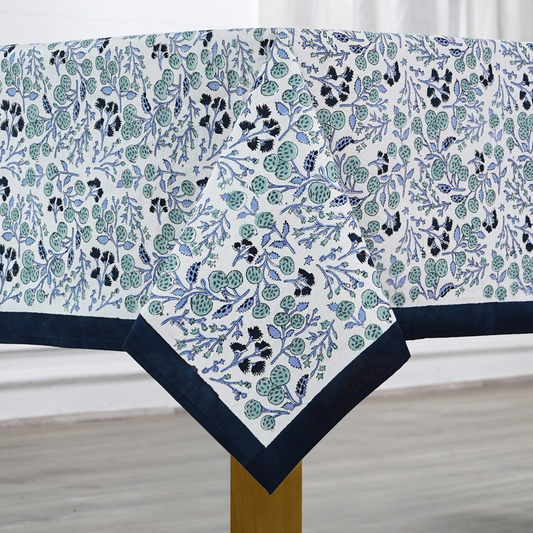 Floral patterned tablecloth with blue border on a wooden table.