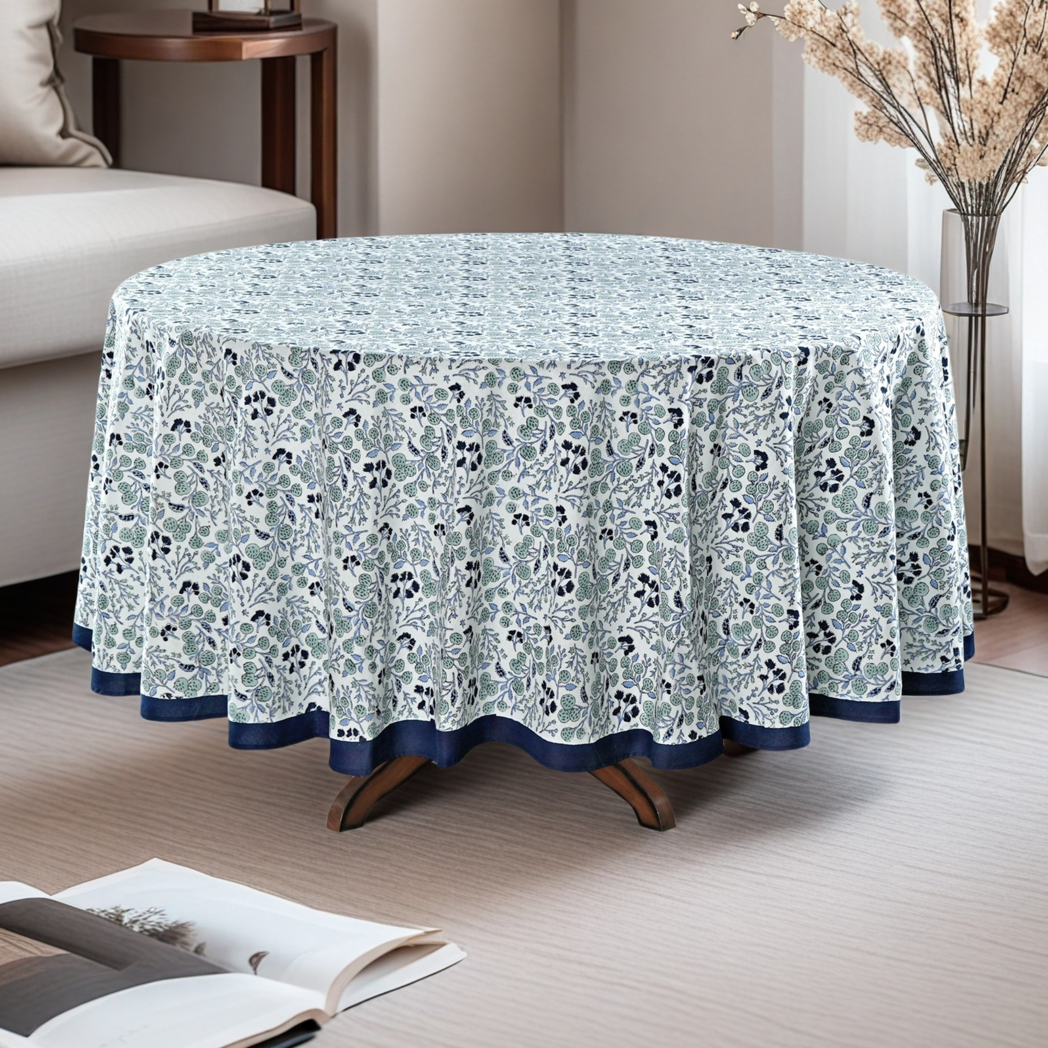 Round table with a floral patterned tablecloth in a living room setting.