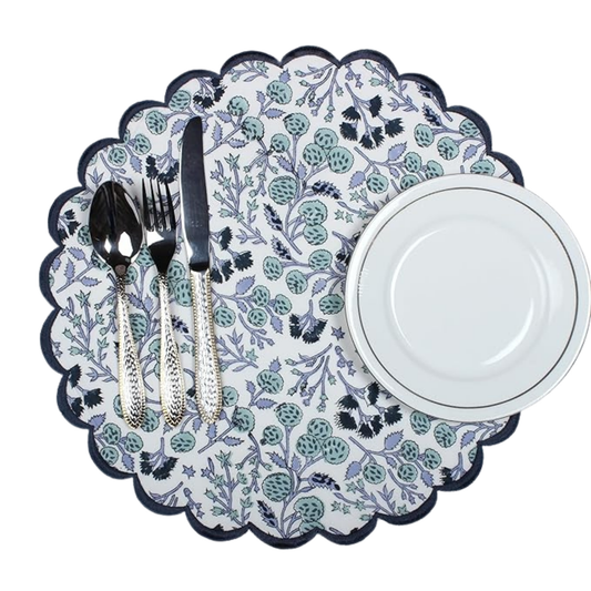 Decorative placemat with floral pattern, cutlery, and a white plate on a white background