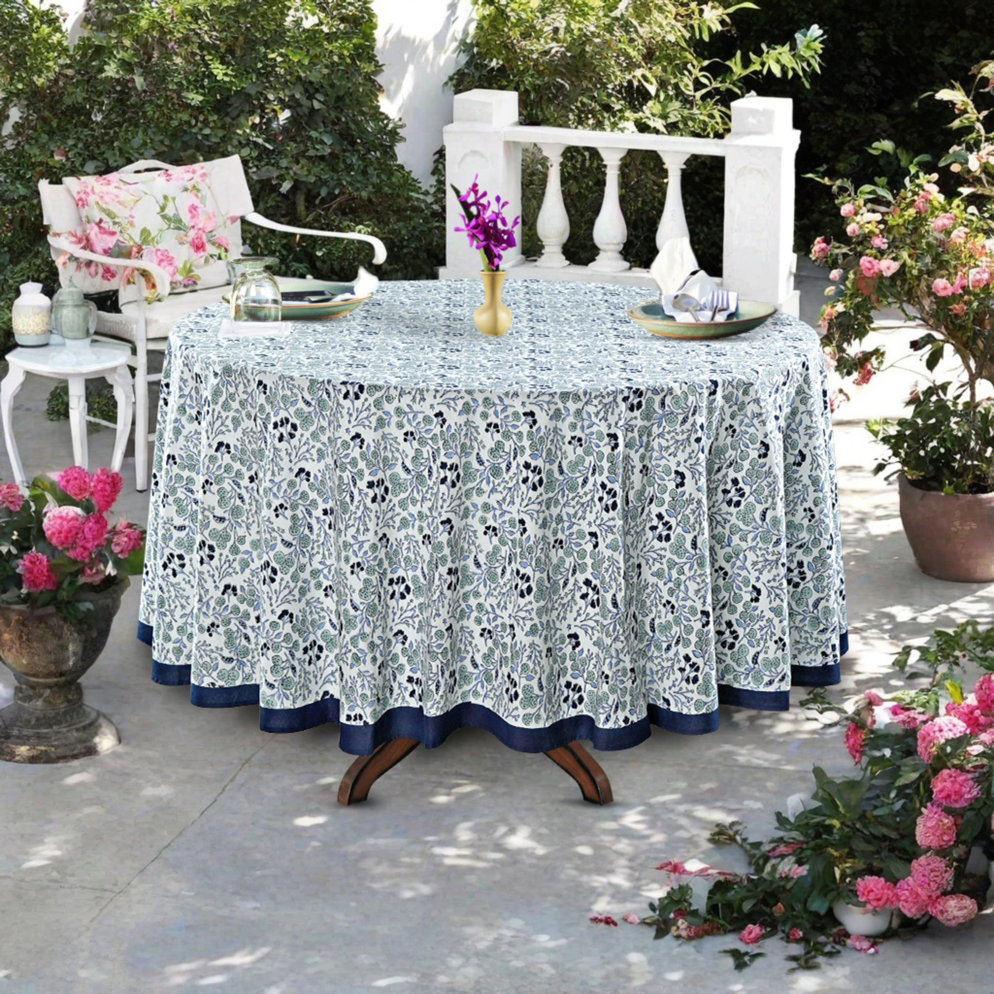 Outdoor table setting with a floral-patterned tablecloth, chairs, and decorative elements.