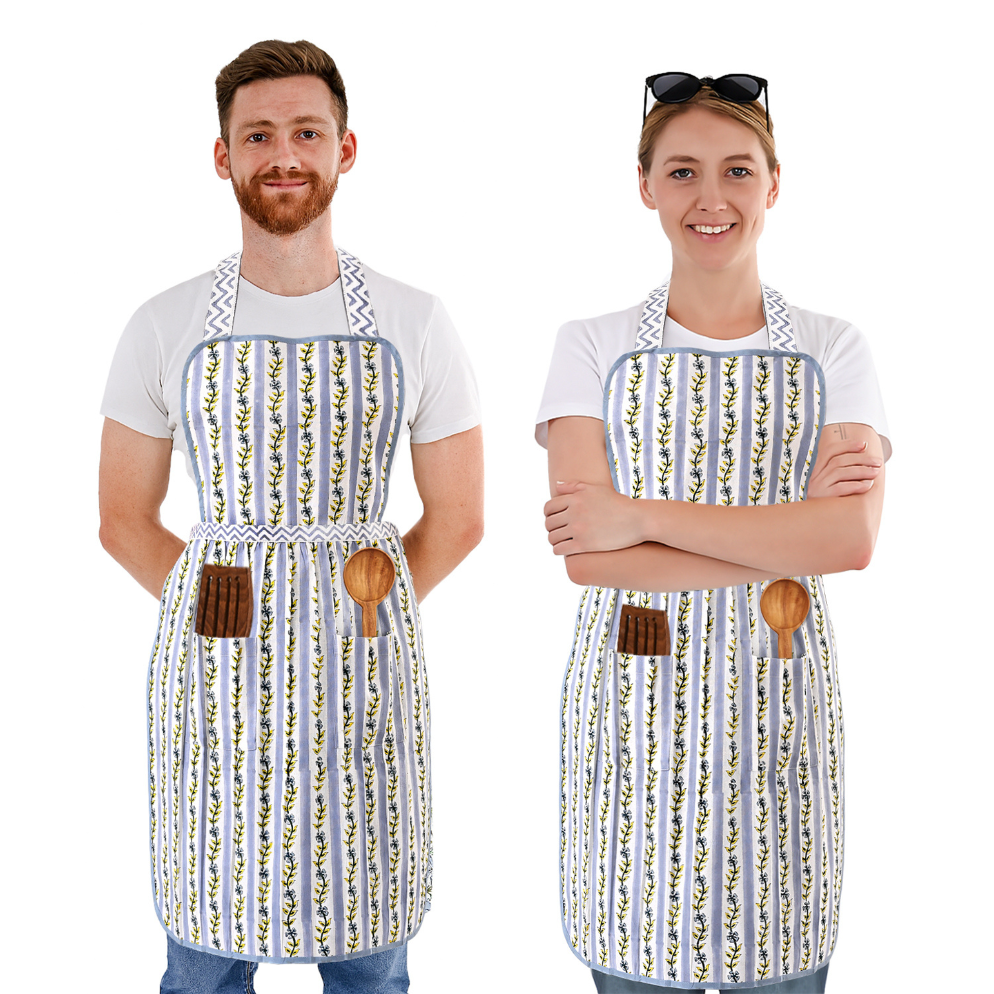 Two people wearing matching aprons with a floral pattern on a white background