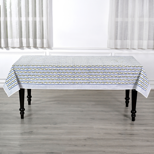 Tablecloth with a subtle pattern on a wooden table in a room with white curtains.