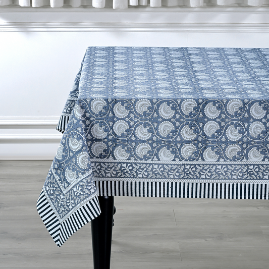 Blue patterned tablecloth on a table with a white wall and wooden floor background