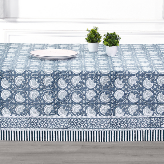 Tablecloth with blue and white pattern on a table with plates and plants.