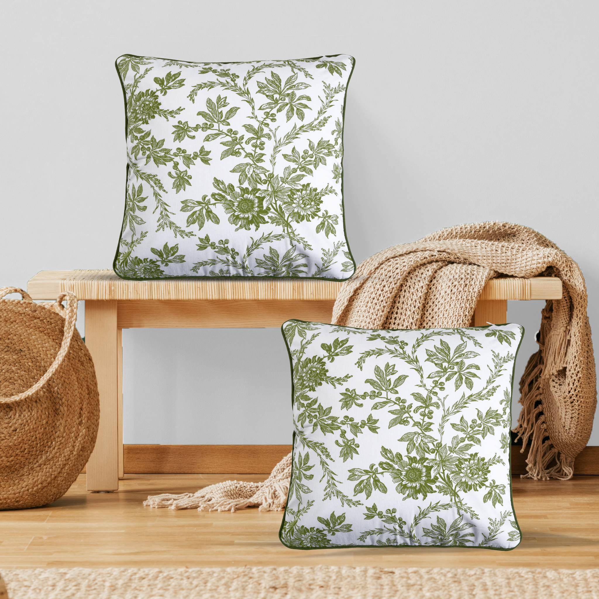 Two green floral-patterned pillows on a wooden surface with a neutral background