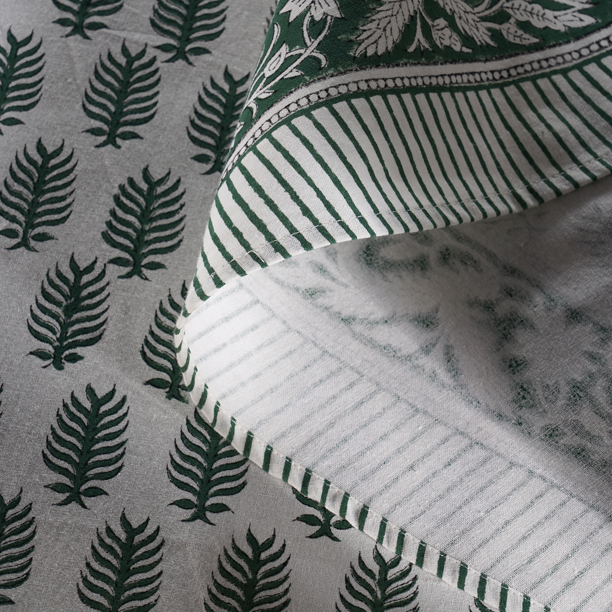 Close-up of fabric with green leaf pattern and striped edge