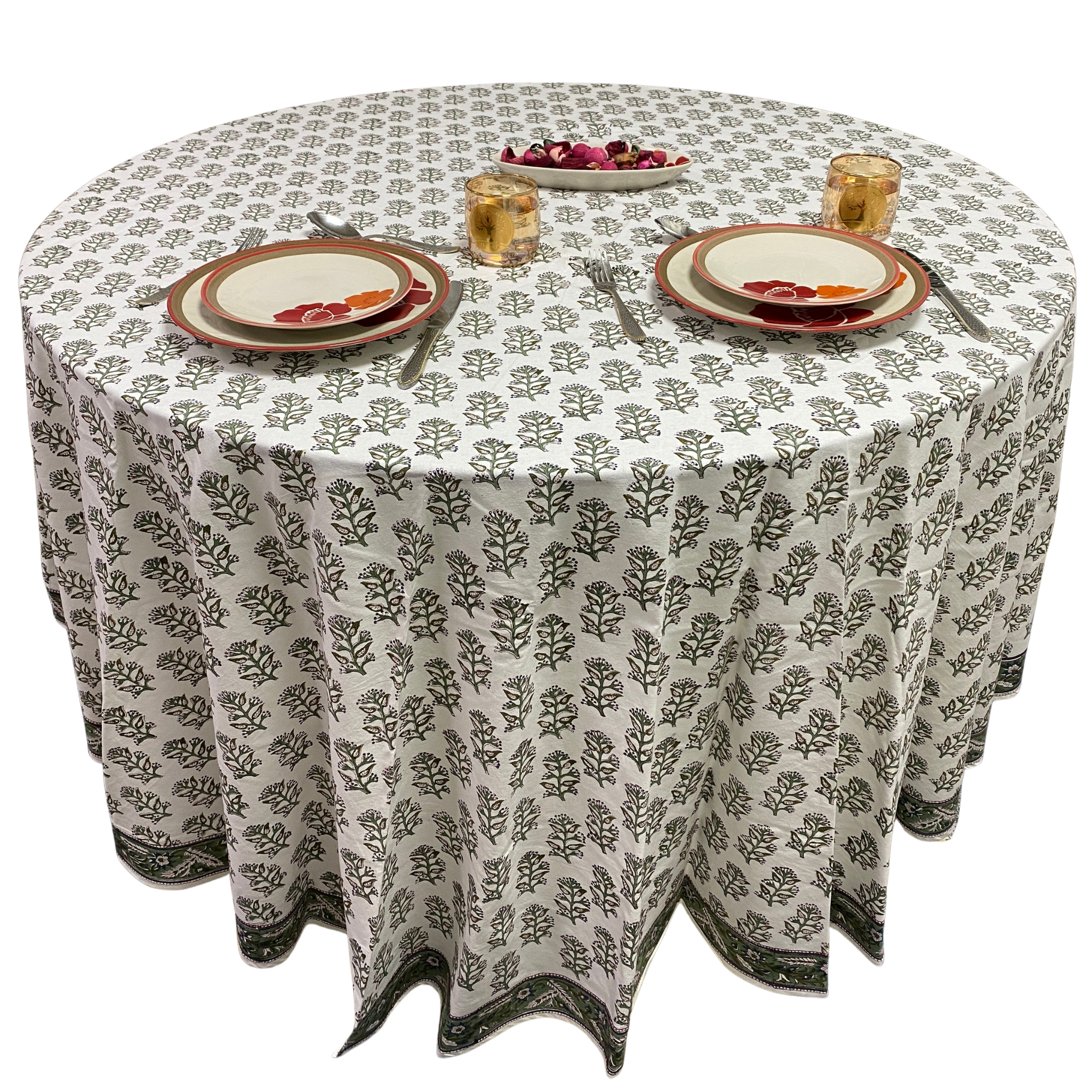 Round table with a patterned tablecloth, plates, and glasses on a white background