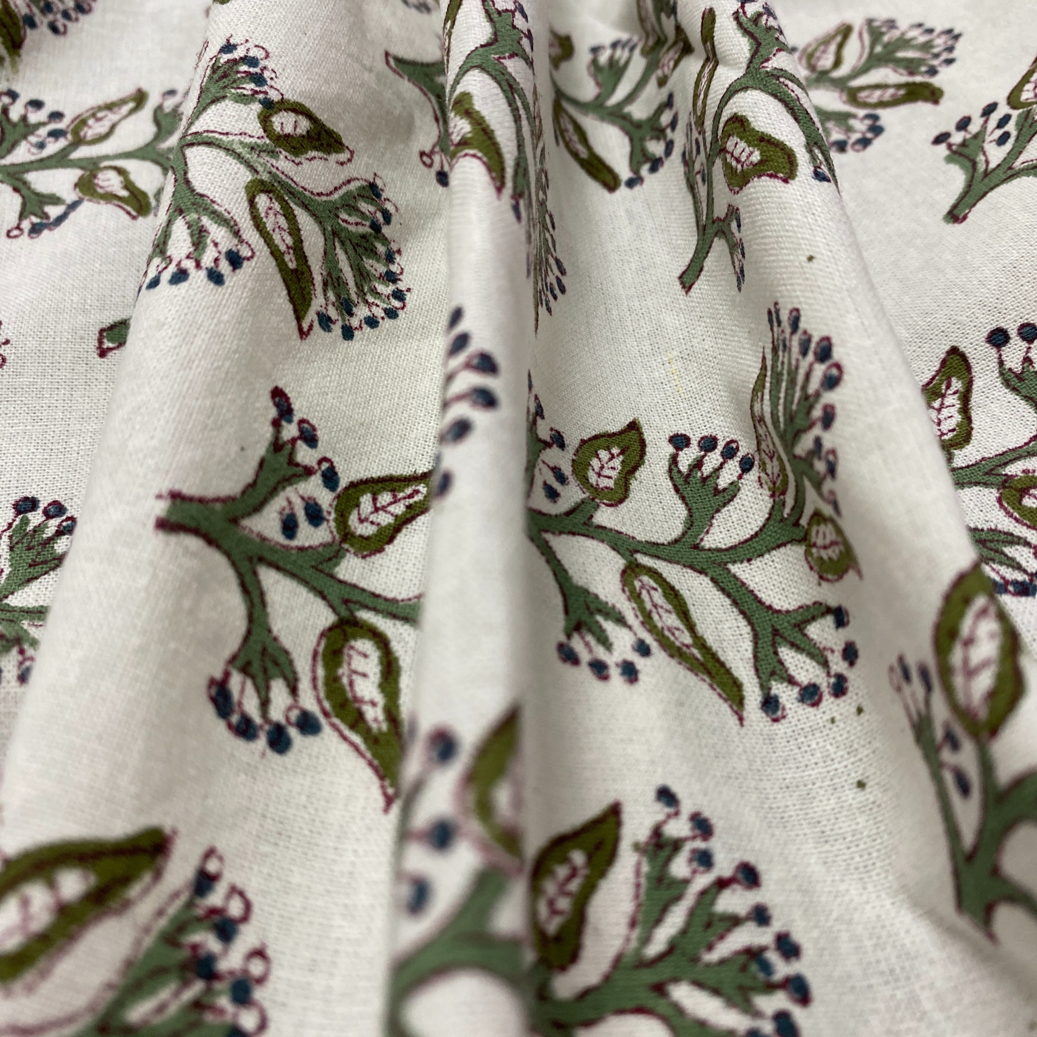 Close-up of fabric with green floral pattern on a white background