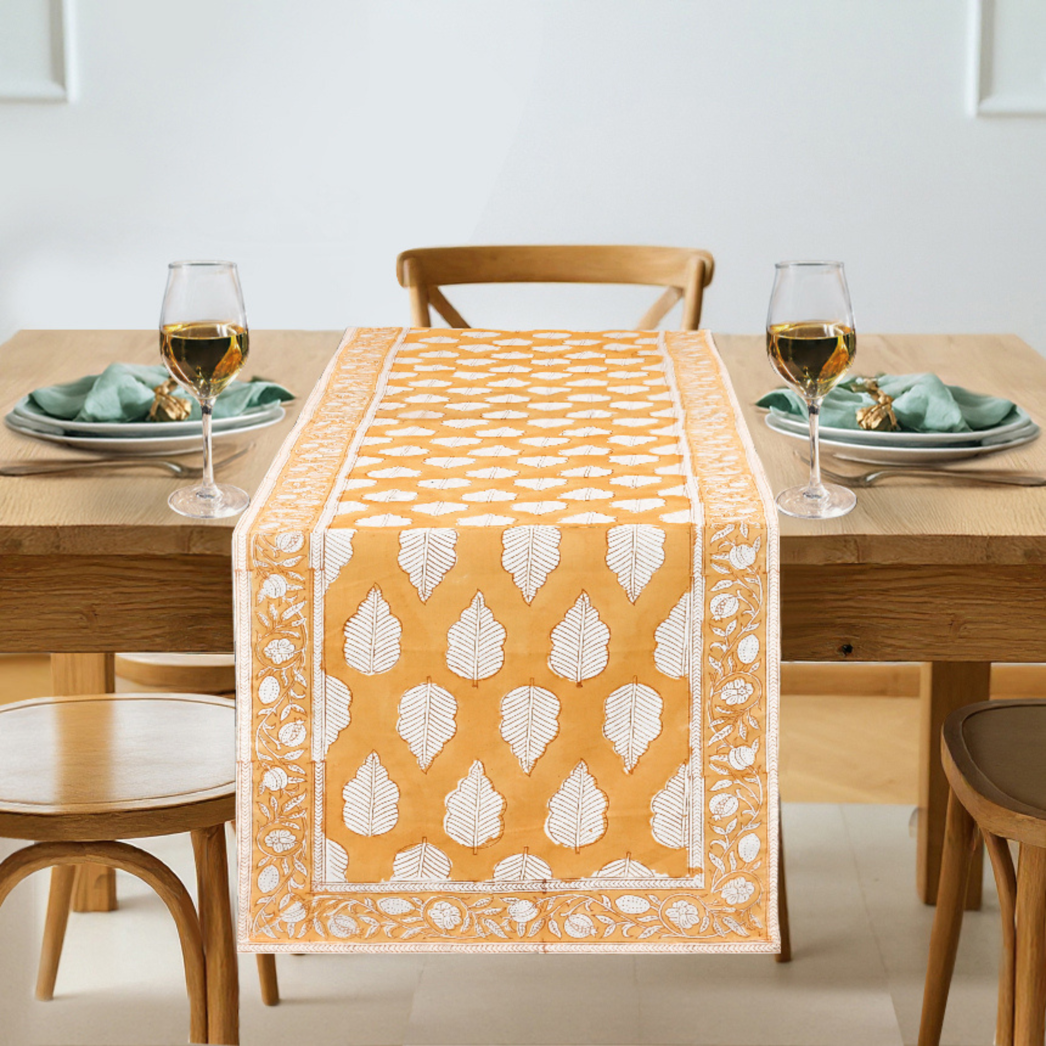 Dining table set with a yellow and white patterned table runner, glasses, and plates.