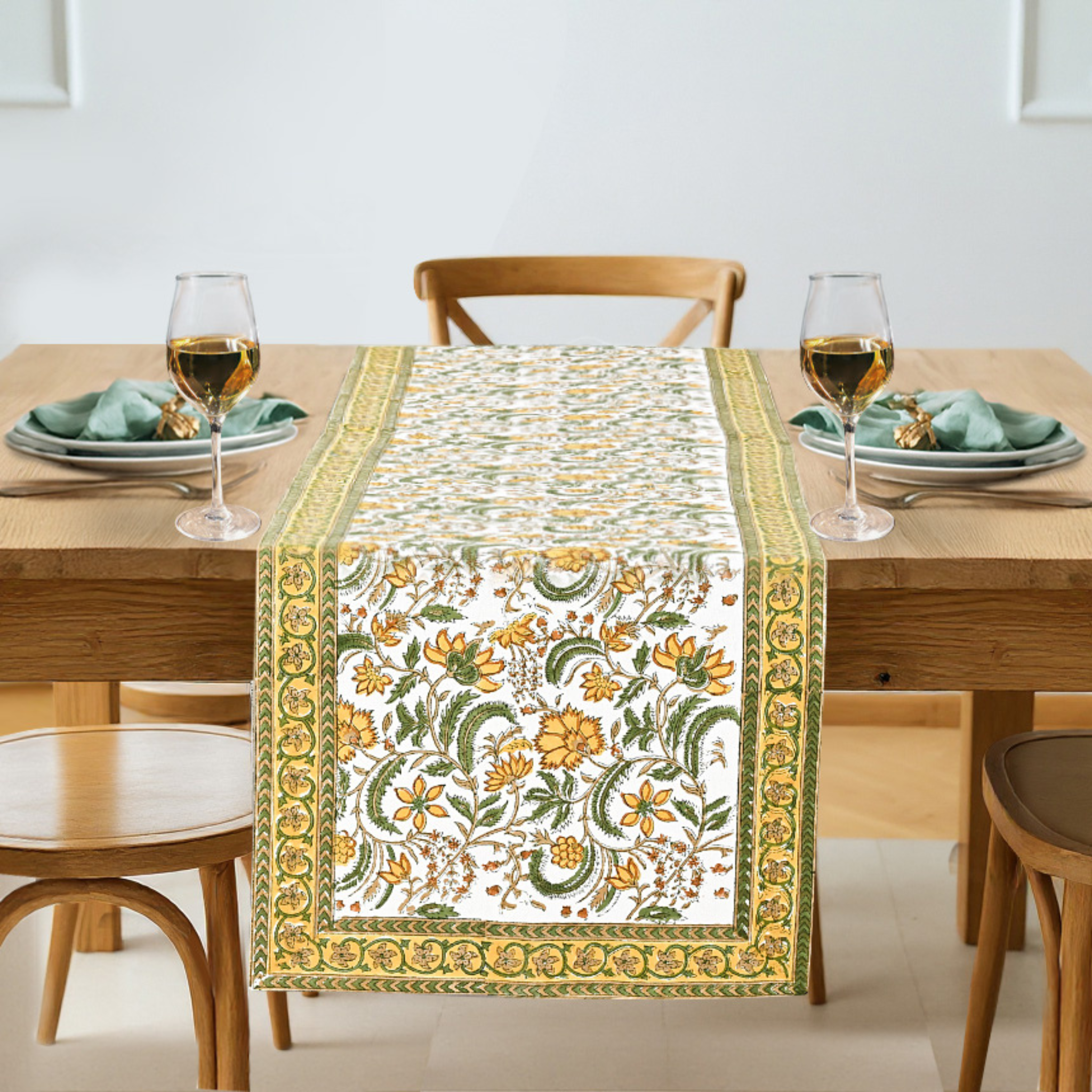 Floral patterned table runner on a wooden table with glasses and plates.