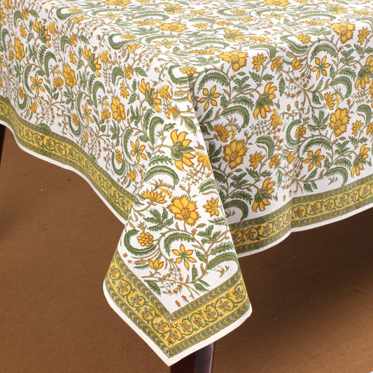 Floral patterned tablecloth with green and yellow design on a brown surface