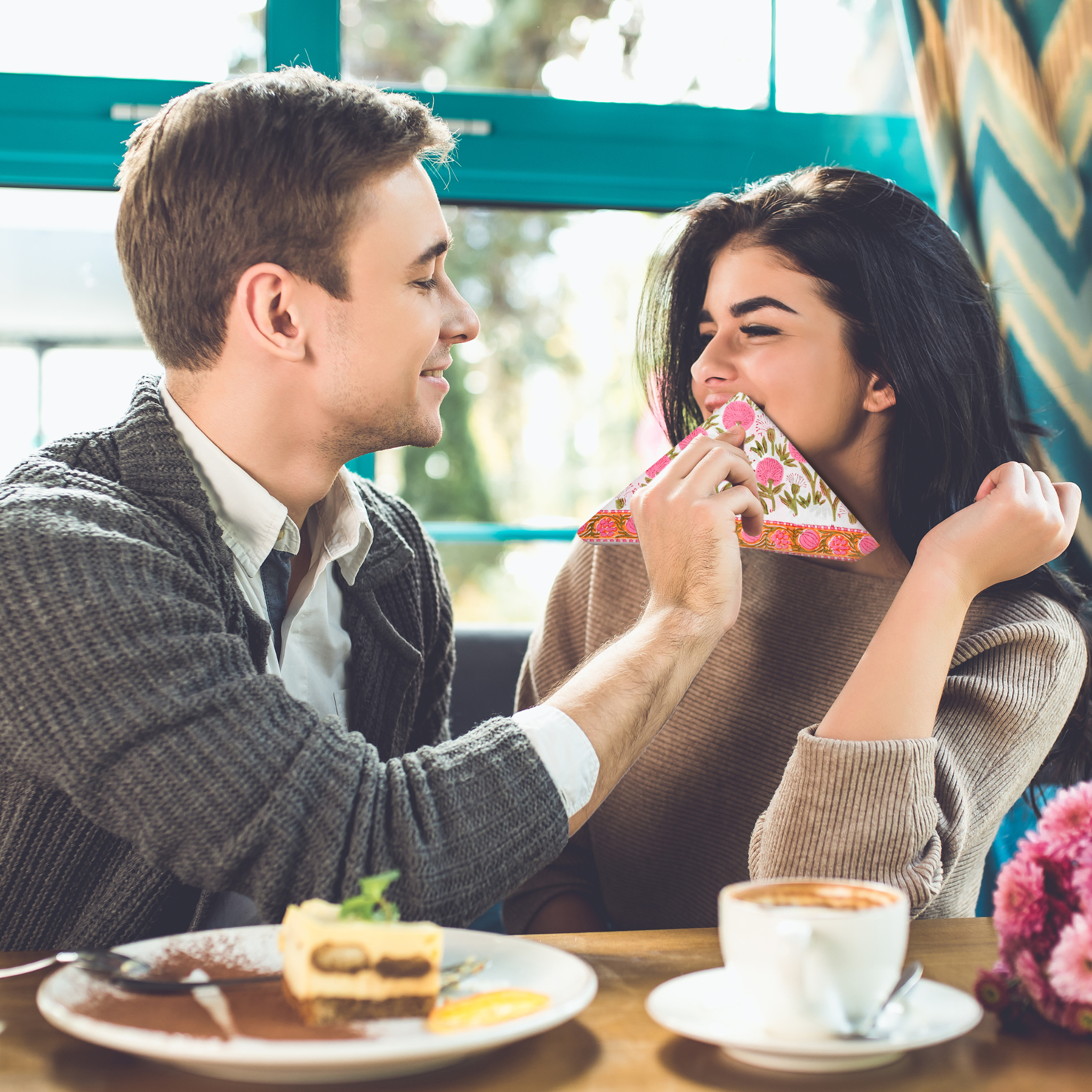 Man and woman sharing a slice of cake in a cafe setting