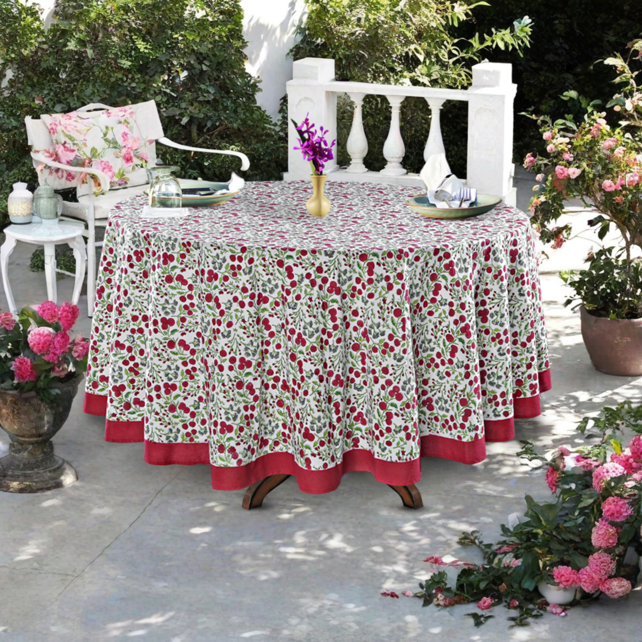 Outdoor table setting with a floral tablecloth, chairs, and decorative elements.