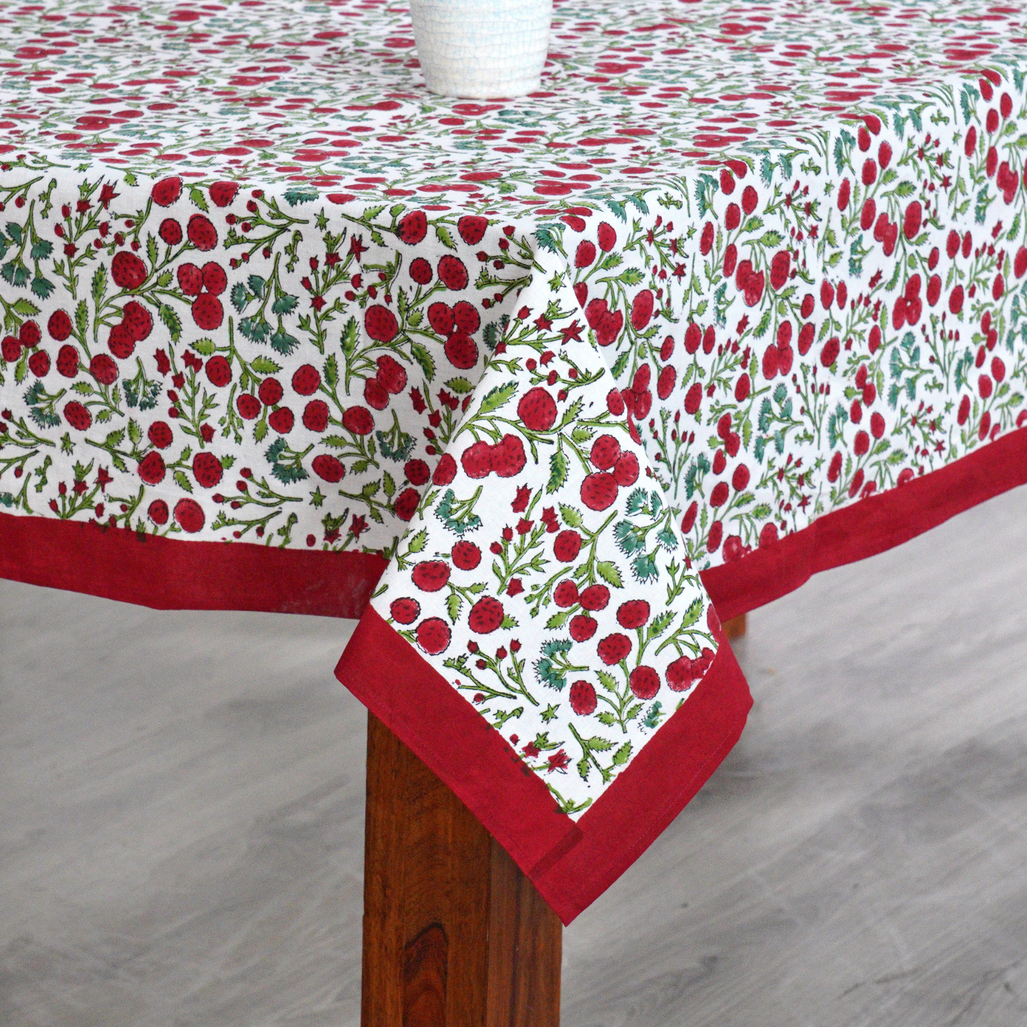Tablecloth with red and green floral pattern on a wooden table