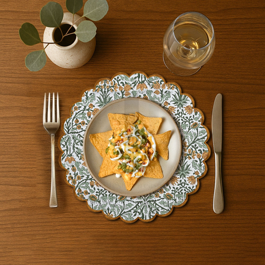 Dinner setting with a decorative plate of nachos, a glass of water, fork, and knife on a wooden table.