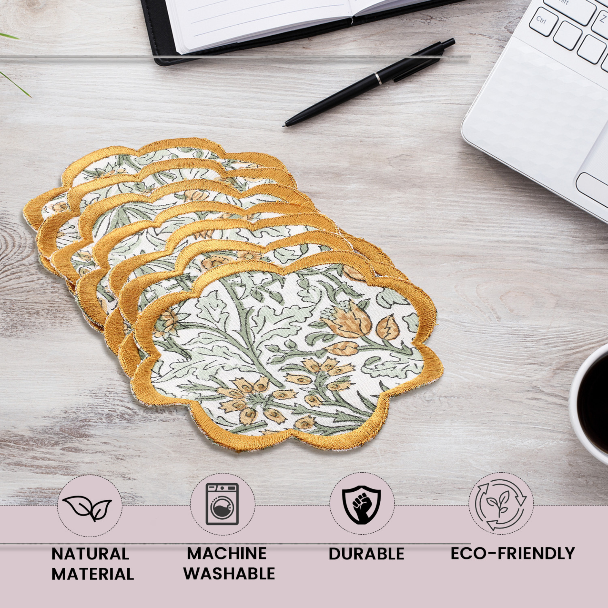 Set of floral coasters on a desk with laptop, pen, and coffee cup.