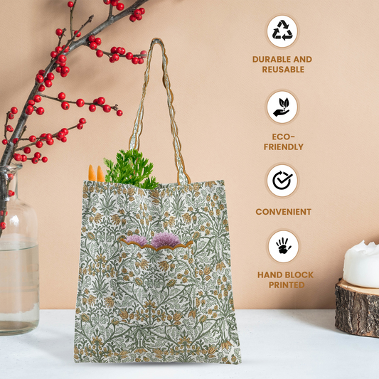 Floral-patterned tote bag with vegetables, next to a branch with red berries and a candle on a white surface.