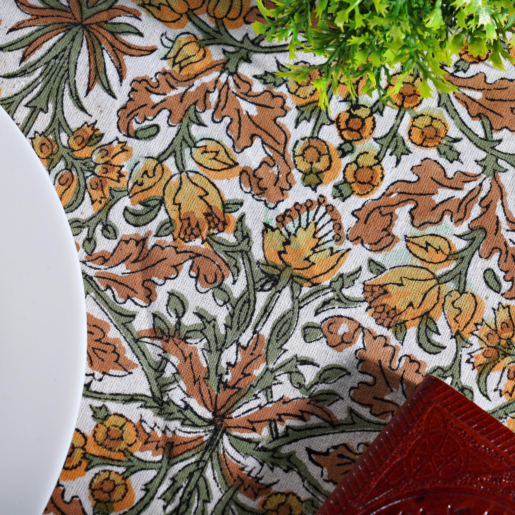 Close-up of a floral patterned fabric with brown, green, and orange colors.