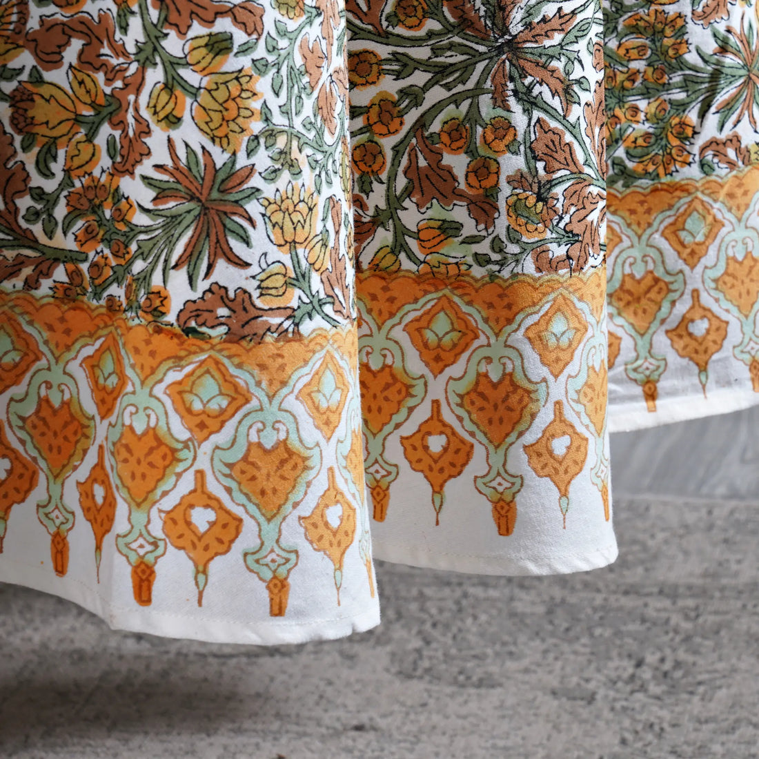 Close-up of patterned fabric with orange, green, and white design on a textured surface.