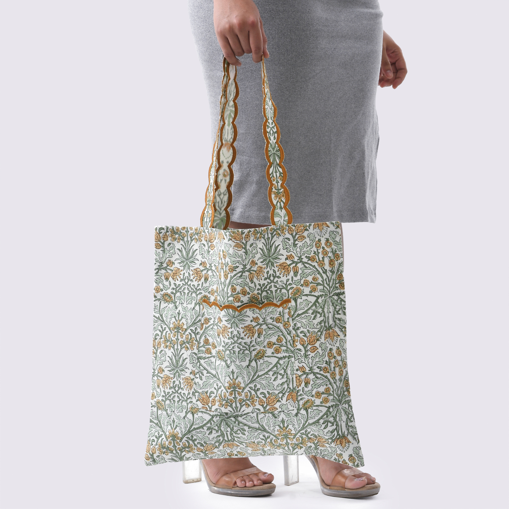 Person holding a floral-patterned tote bag against a plain background