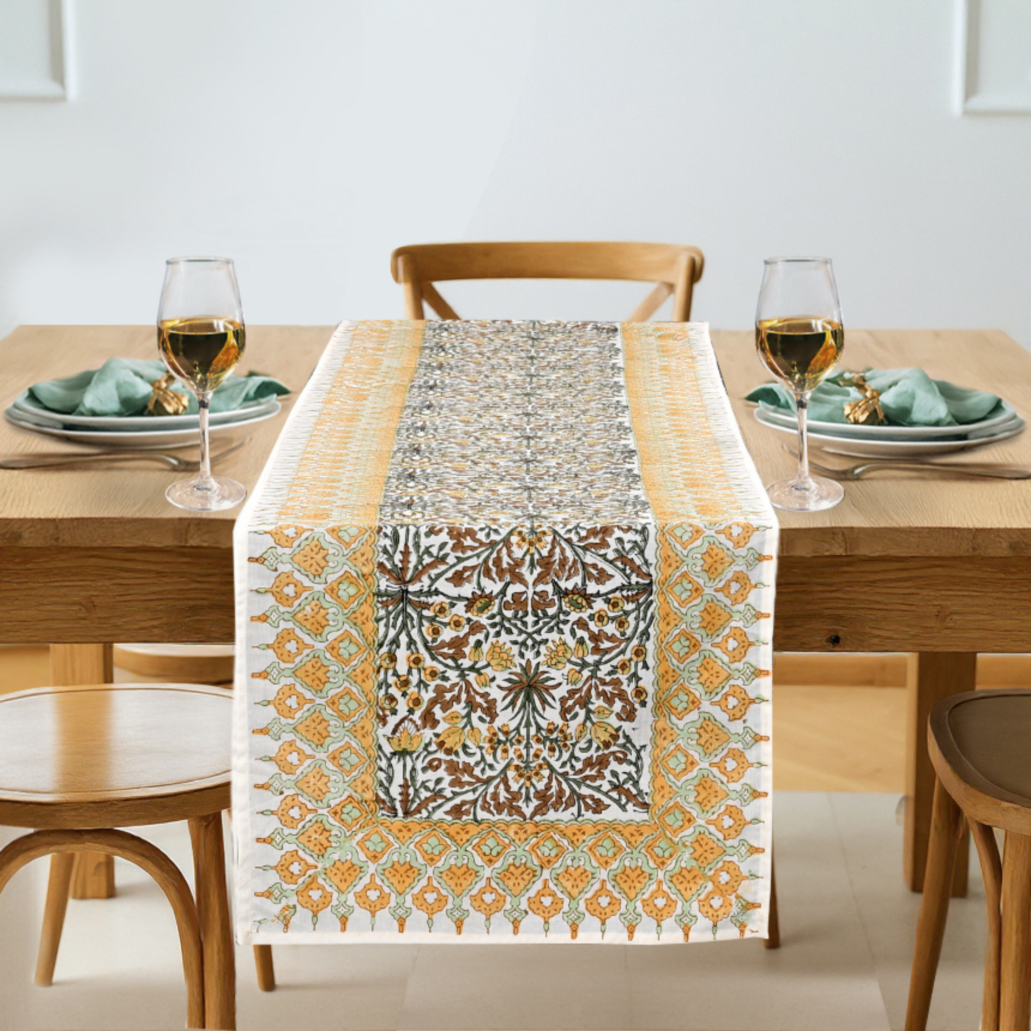 Dining table set with a patterned table runner, glasses, and plates.