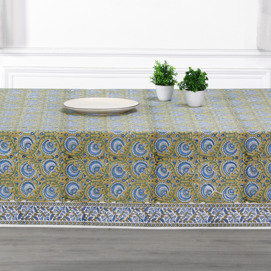 Tablecloth with a floral pattern on a dining table with plates and plants.