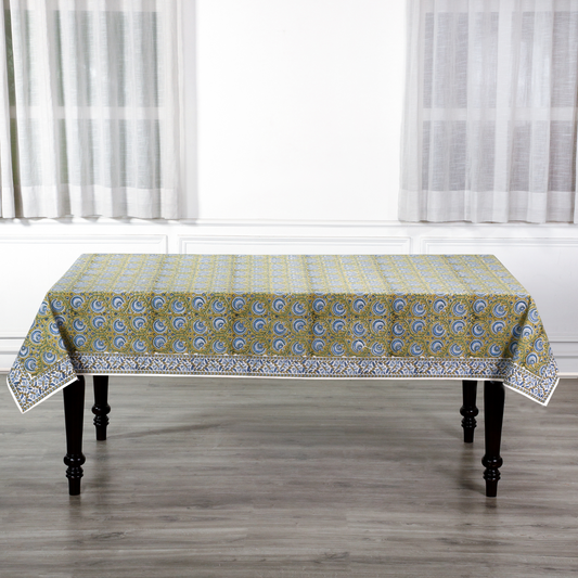 Patterned tablecloth on a wooden table with white curtains in the background