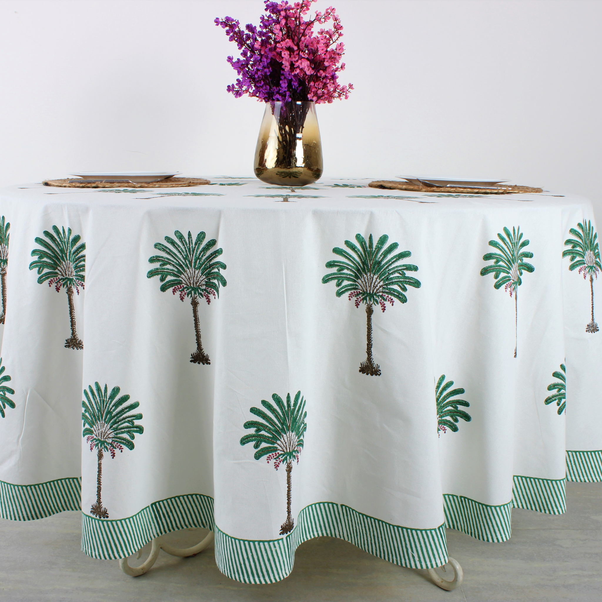 Tablecloth with palm tree design on a table with a vase of flowers.