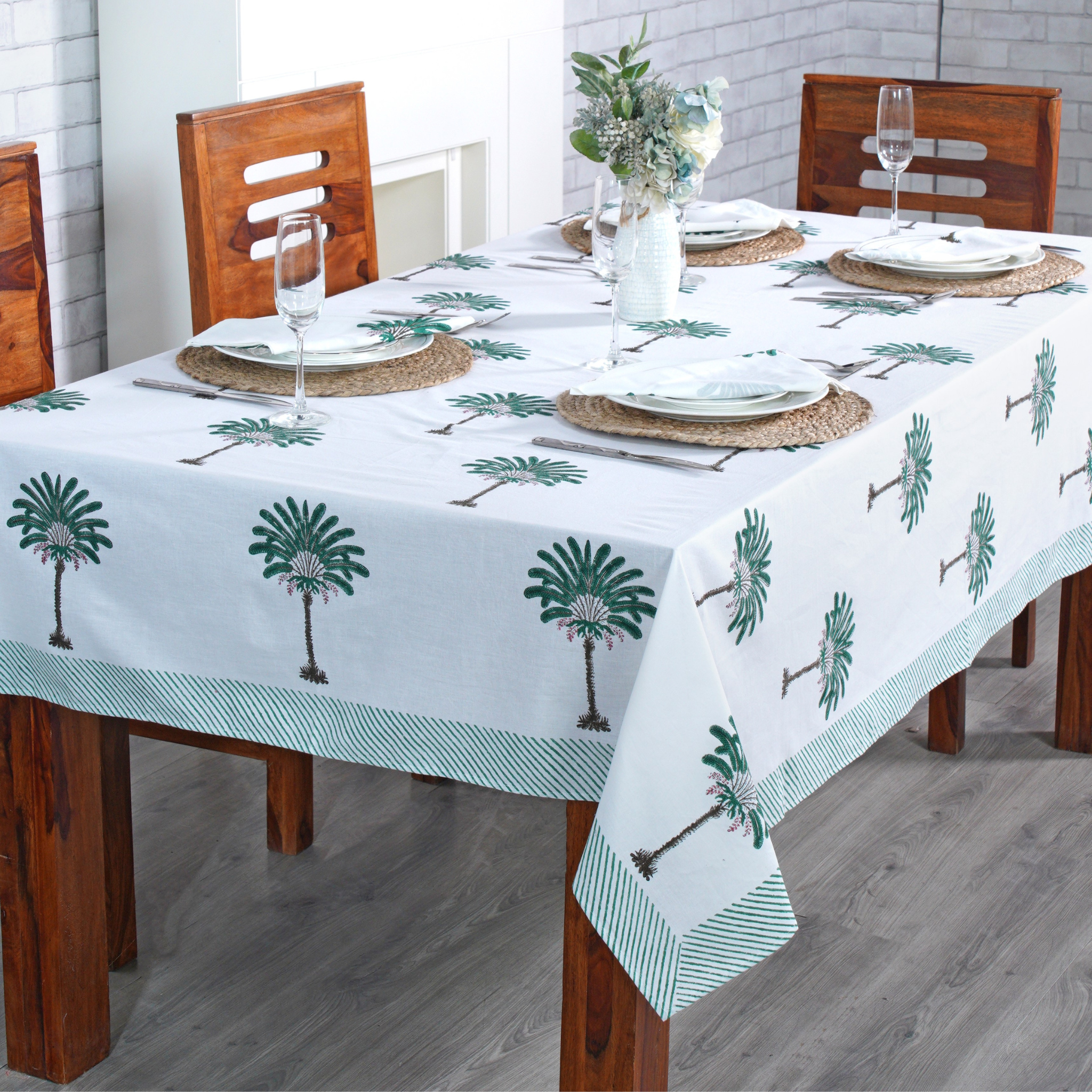 Dining table set with a palm tree patterned tablecloth on a wooden table.