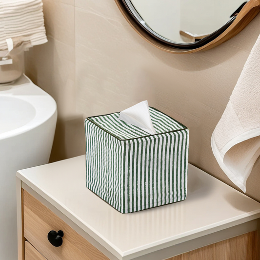 Green and white striped tissue box on a bathroom counter with a sink and mirror in the background.