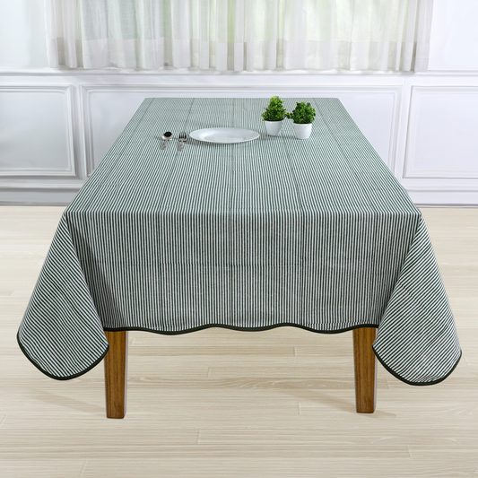 Tablecloth with green and white stripes on a wooden table in a room with white walls and curtains.