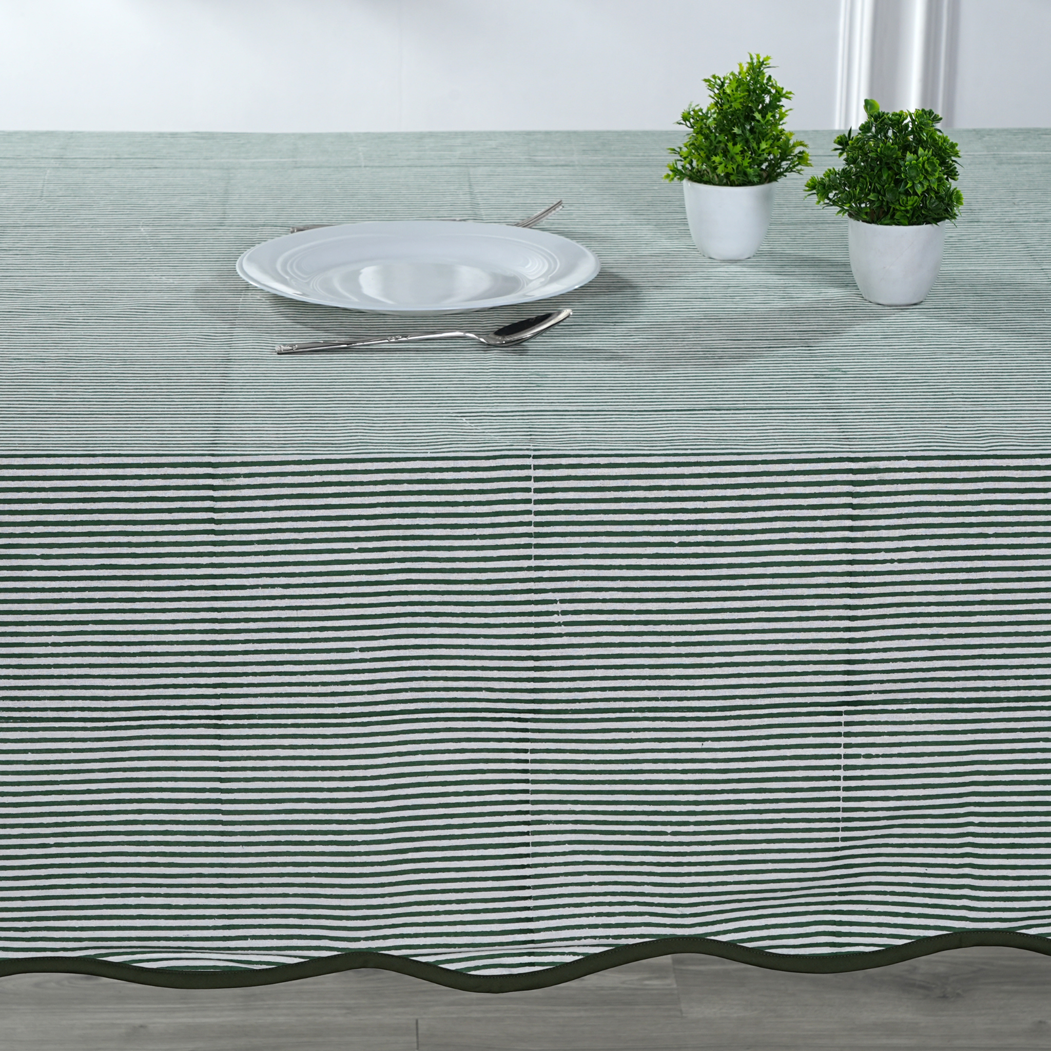 Tablecloth with black stripes on a table setting with a plate, cutlery, and plants.