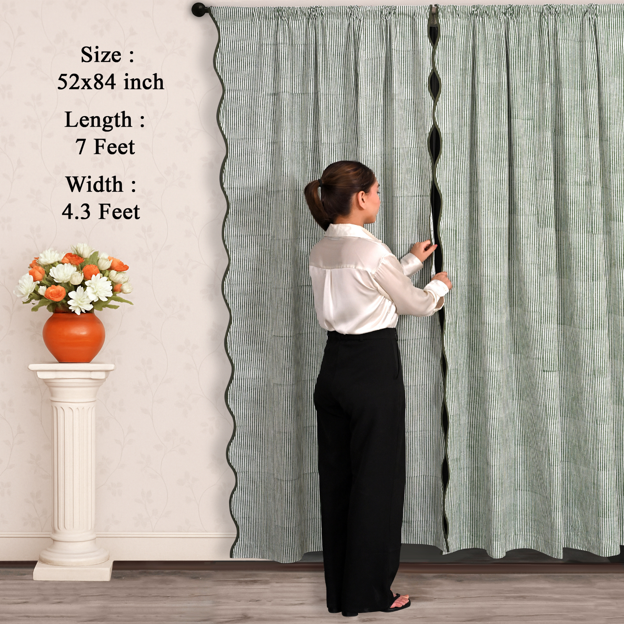 Woman adjusting a long curtain with text displaying dimensions, next to a small table with flowers.